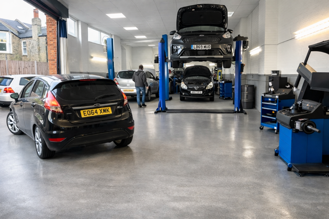A white car on a ramp with a technician working underneath.